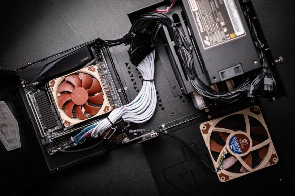 This photo shows the 45HomeLab HL4 enclosure unfolded. The left site and front side are piano-hinged to the base. Captive screws secure the two panels in the closed position. The motherboard is mounted to the left side. The CPU cooler fan covers most of the board. Drive cables run from the front edge of the motherboard to the drive board at the rear. The 4 bay drive cage is in the upper right under the small form factor power supply. The drive cooling fan is mounted on the front plate.